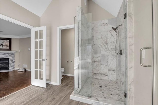 bathroom featuring toilet, french doors, a tiled fireplace, and vaulted ceiling