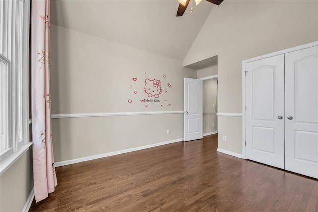 unfurnished bedroom with ceiling fan, dark hardwood / wood-style flooring, a closet, and high vaulted ceiling