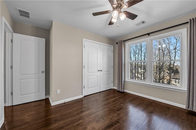 unfurnished bedroom with multiple windows, a closet, ceiling fan, and dark wood-type flooring