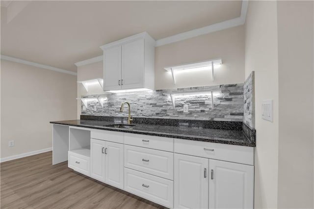 kitchen featuring sink, white cabinetry, dark stone countertops, ornamental molding, and decorative backsplash