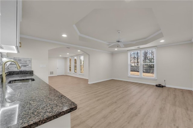 living room featuring sink, crown molding, light hardwood / wood-style flooring, and a raised ceiling