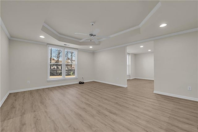 unfurnished room with a raised ceiling, ornamental molding, ceiling fan, and light hardwood / wood-style flooring