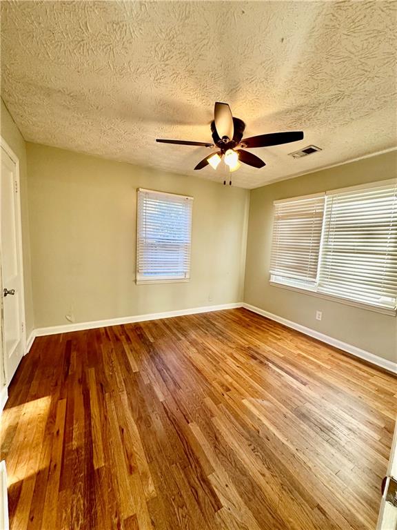 unfurnished room with hardwood / wood-style floors and a textured ceiling