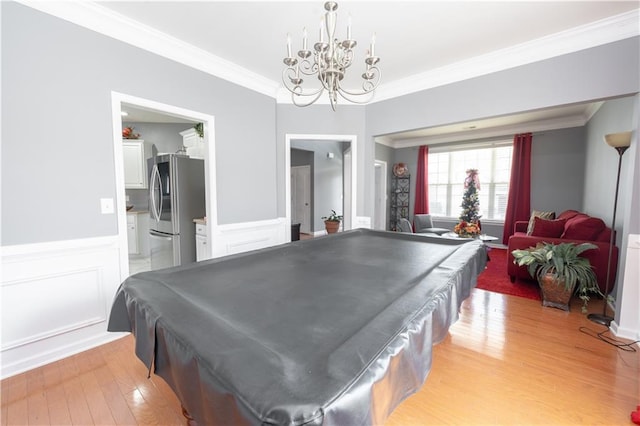 recreation room featuring crown molding, a decorative wall, wainscoting, light wood-type flooring, and billiards