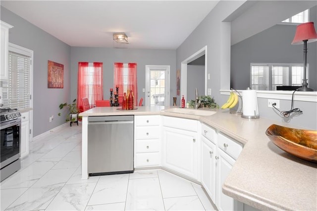 kitchen with stainless steel appliances, marble finish floor, light countertops, and a sink