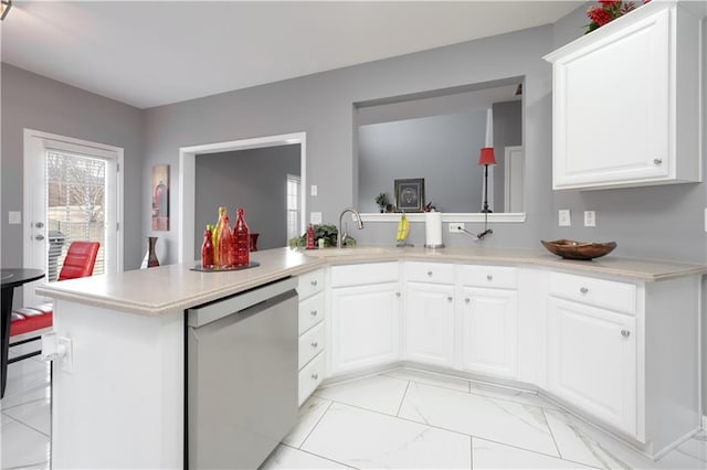 kitchen featuring a sink, marble finish floor, light countertops, and stainless steel dishwasher