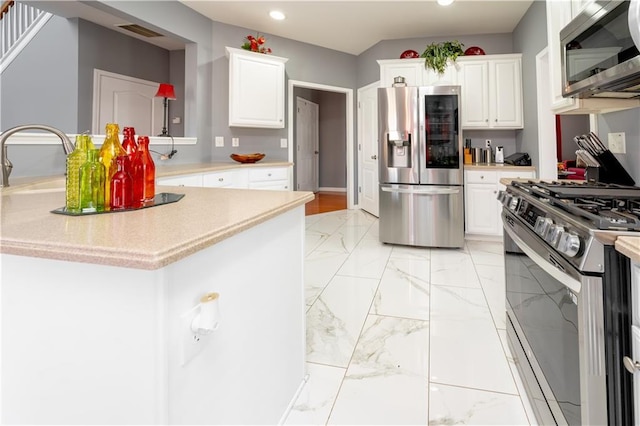 kitchen featuring marble finish floor, stainless steel appliances, light countertops, and white cabinetry