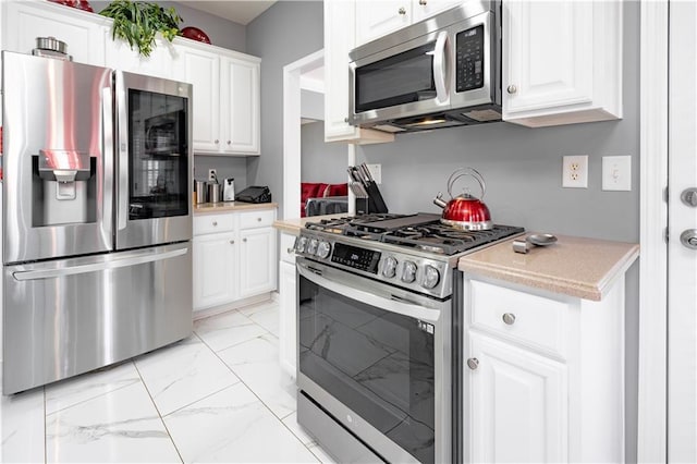 kitchen with appliances with stainless steel finishes, marble finish floor, light countertops, and white cabinetry