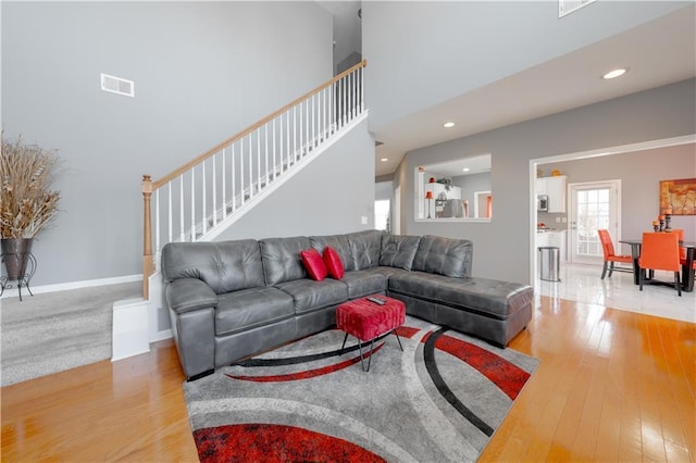 living area featuring baseboards, visible vents, hardwood / wood-style floors, and stairs