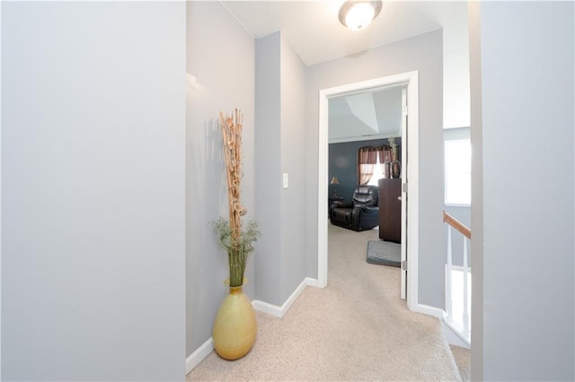 hallway featuring light carpet, an upstairs landing, and baseboards