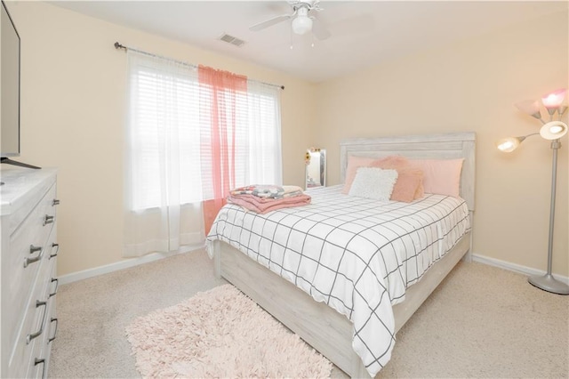 bedroom with light carpet, ceiling fan, visible vents, and baseboards