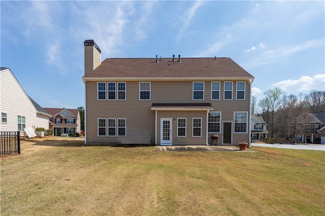 back of property with a patio area, a lawn, and a chimney