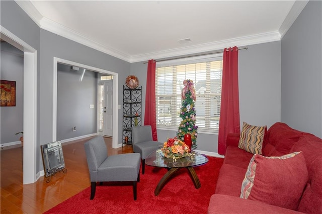 living room featuring ornamental molding, visible vents, baseboards, and wood finished floors