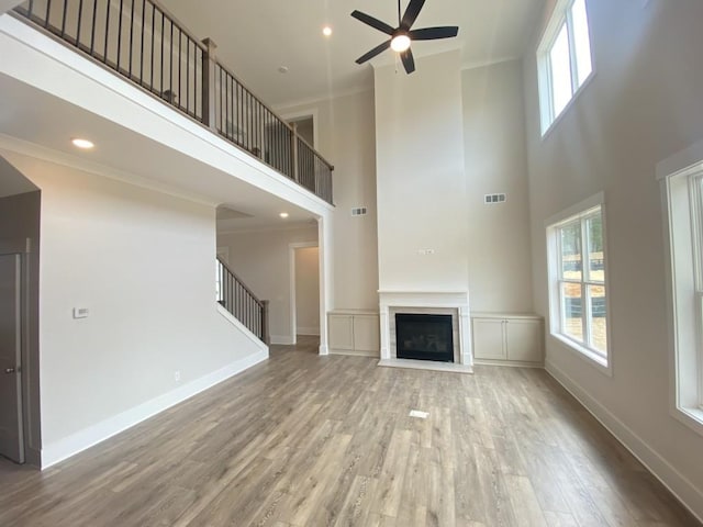 unfurnished living room with a fireplace with flush hearth, wood finished floors, visible vents, and baseboards