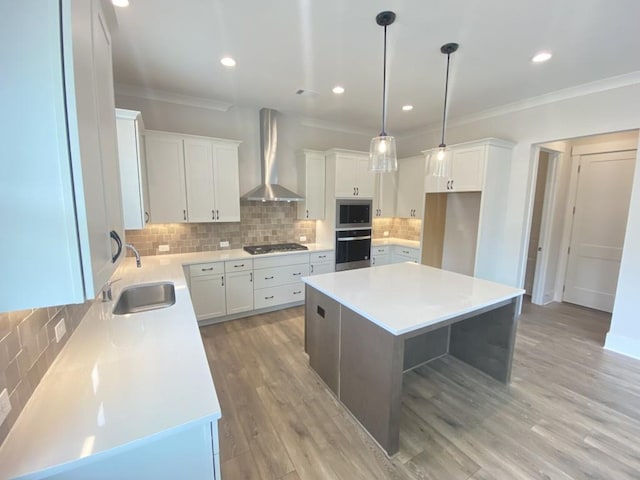 kitchen featuring wall chimney exhaust hood, ornamental molding, a sink, and stainless steel appliances