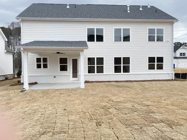 rear view of property featuring brick siding, roof with shingles, a ceiling fan, and a patio