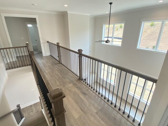 hallway with a healthy amount of sunlight, crown molding, wood finished floors, and recessed lighting