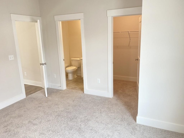 unfurnished bedroom with carpet floors, baseboards, a walk in closet, and a closet