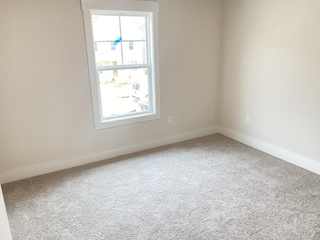 carpeted spare room featuring baseboards