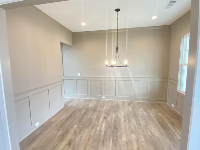 unfurnished dining area with recessed lighting, visible vents, a decorative wall, an inviting chandelier, and light wood-style floors