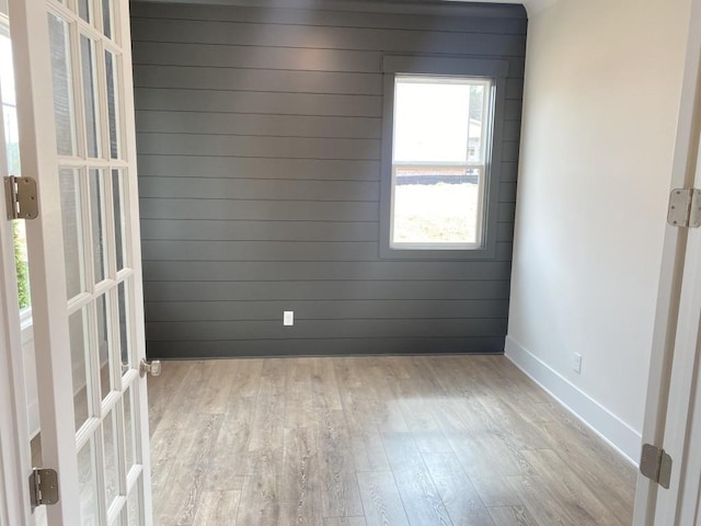 spare room with wooden walls, baseboards, wood finished floors, and french doors