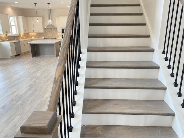 stairway with wood finished floors and recessed lighting