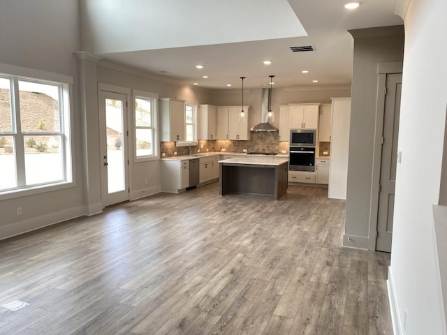 kitchen with stainless steel appliances, tasteful backsplash, light countertops, visible vents, and wall chimney exhaust hood