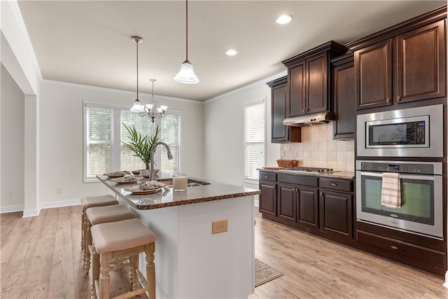 kitchen featuring ornamental molding, appliances with stainless steel finishes, dark stone counters, and a sink