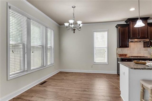 unfurnished dining area with visible vents, baseboards, light wood finished floors, ornamental molding, and a chandelier