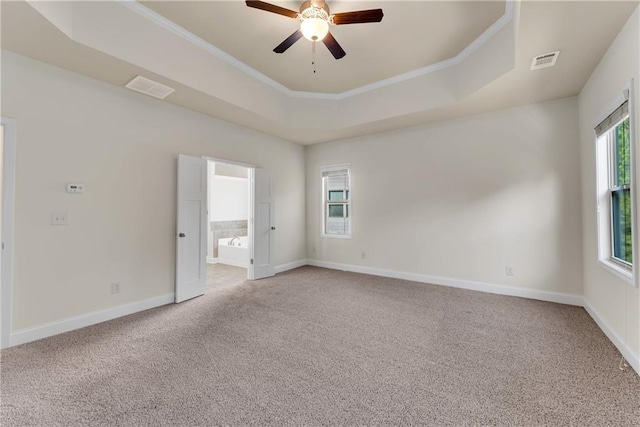 empty room featuring baseboards, visible vents, a raised ceiling, and light carpet