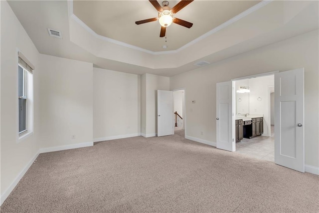 unfurnished bedroom featuring light carpet, visible vents, crown molding, and a tray ceiling