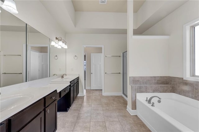 full bath with a sink, a garden tub, double vanity, and tile patterned flooring