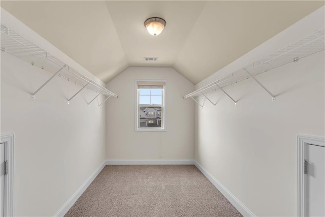 spacious closet with lofted ceiling, light colored carpet, and visible vents