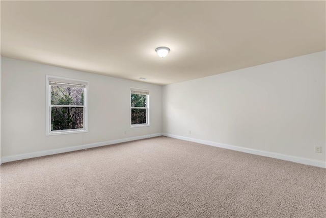 unfurnished room featuring light colored carpet and baseboards