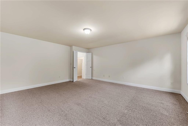 empty room featuring light colored carpet and baseboards