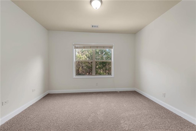 carpeted spare room featuring baseboards and visible vents