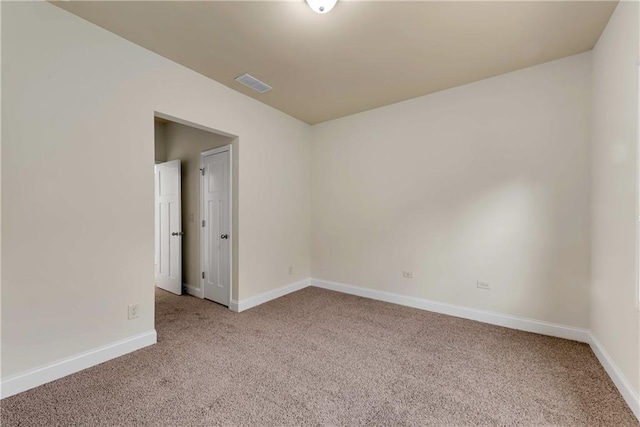 carpeted spare room with visible vents and baseboards