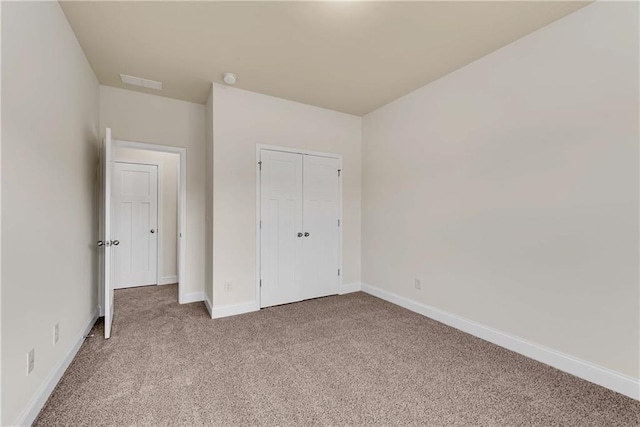 unfurnished bedroom with visible vents, carpet floors, baseboards, and a closet