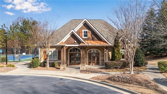 view of front of property with french doors, roof with shingles, and fence