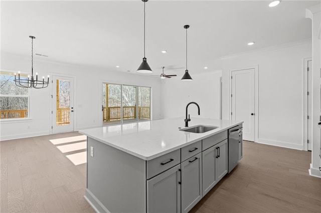 kitchen featuring sink, gray cabinetry, dishwasher, pendant lighting, and a kitchen island with sink