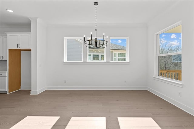 unfurnished dining area featuring ornamental molding, light hardwood / wood-style floors, and a chandelier