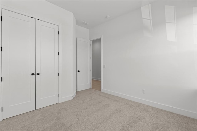 unfurnished bedroom featuring a closet and light carpet