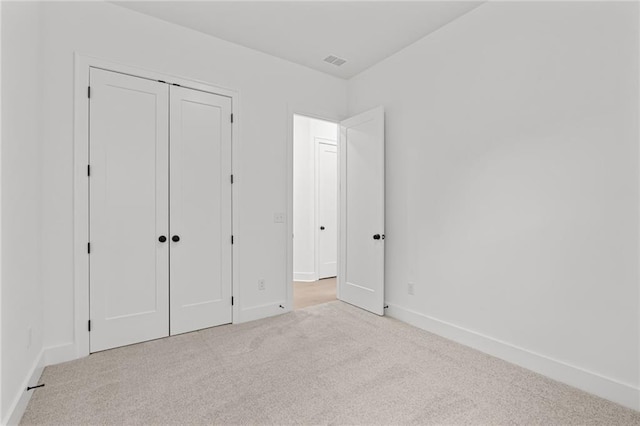 unfurnished bedroom with light colored carpet and a closet