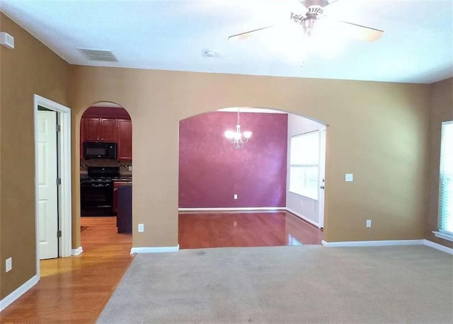 spare room with ceiling fan with notable chandelier and wood-type flooring