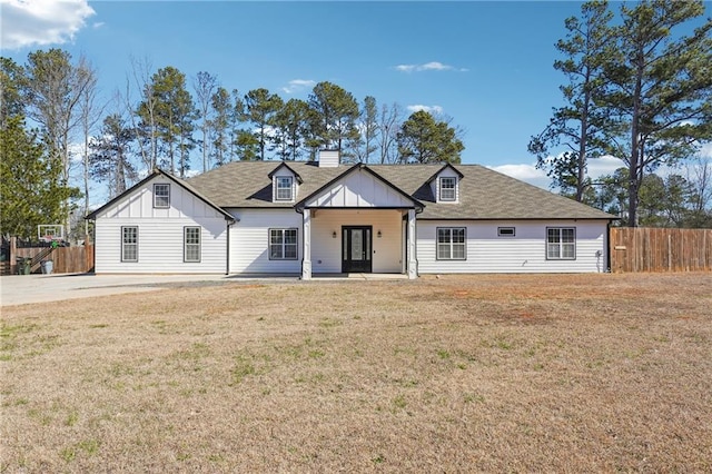 view of front of home featuring a chimney, fence, a front lawn, and board and batten siding