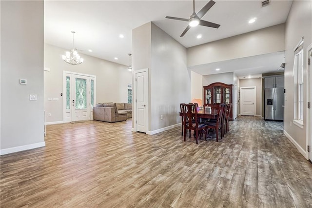 dining space with a towering ceiling, baseboards, wood finished floors, and recessed lighting