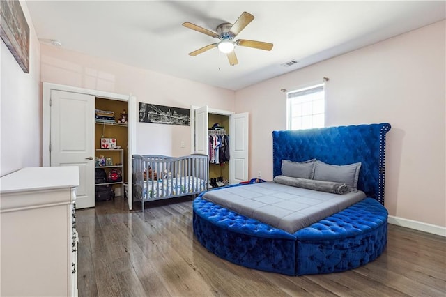 bedroom featuring ceiling fan, wood finished floors, visible vents, and baseboards