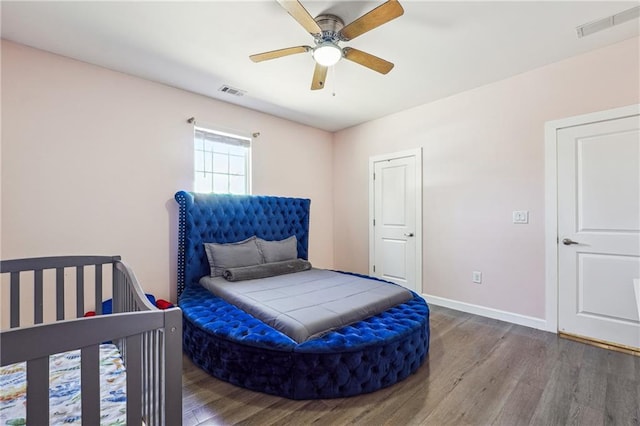 bedroom with wood finished floors, visible vents, and baseboards