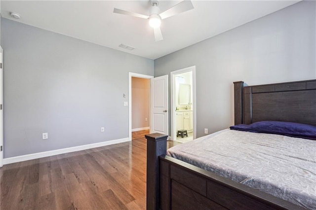 bedroom featuring baseboards, visible vents, ensuite bath, ceiling fan, and wood finished floors