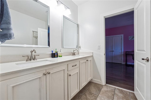 bathroom featuring double vanity, tile patterned flooring, baseboards, and a sink